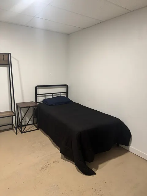 Bedroom at the 2091 4th Ave E house with a twin bed, side table and coat rack