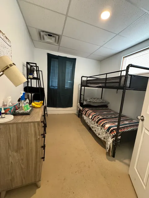 Bedroom at the 2091 4th Ave E house with a black metal bunk bed, dresser, lamp and corner shelf