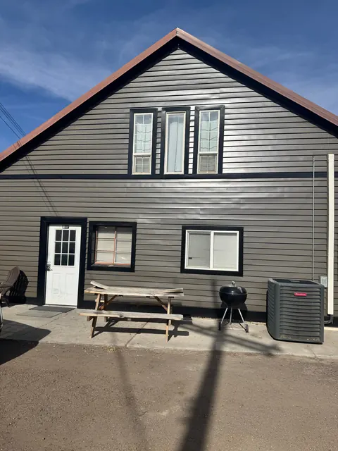 Gable end of the 2091 4th Ave E house with picnic table, grill and AC unit on the patio