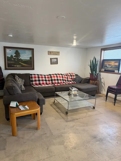 Living room at the 2091 4th Ave E house with a gray sectional, glass coffee table, snake plant and paintings