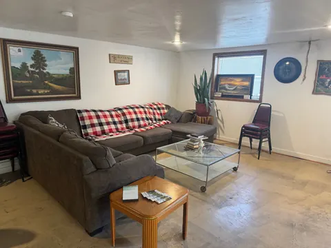Living room at the 2091 4th Ave E house with a sectional sofa, glass coffee table, wall clock and window