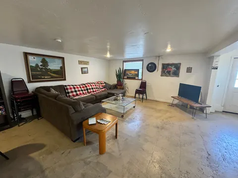 Wide view of the living room at the 2091 4th Ave E house with a sectional sofa, TV bench and entry door