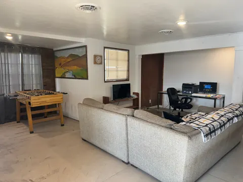 Common room at the 2091 4th Ave E house with a sectional sofa, foosball table, TV and computer desk