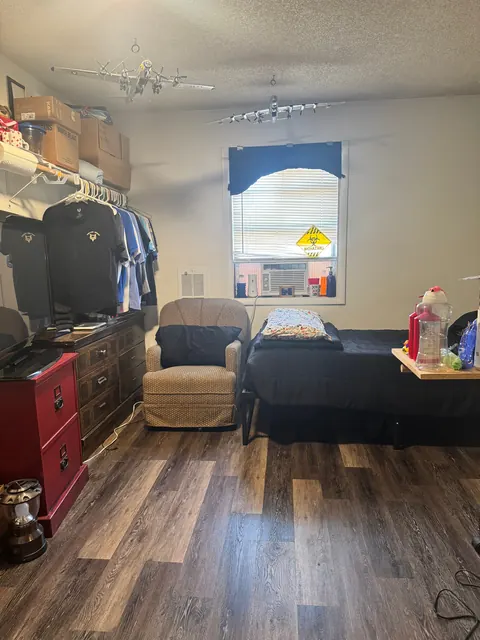 Bedroom at the 212 4th Ave E house with a twin bed, armchair, dresser, open closet and window AC unit