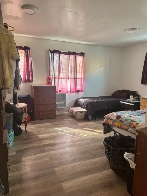 Shared bedroom at the 212 4th Ave E house with two beds, a wood dresser and pink curtains