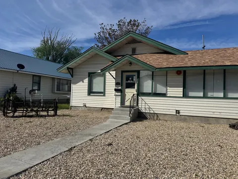Front of the 212 4th Ave E house, a white bungalow with green trim and a gravel yard