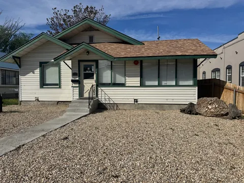 Front of the 212 4th Ave E house with a gravel yard, boulder and weathered stumps