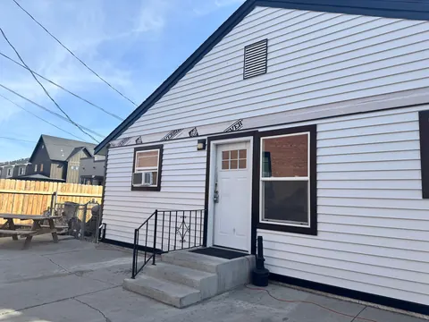 Rear entrance of the 212 4th Ave E house with concrete steps, iron railing, patio and picnic table