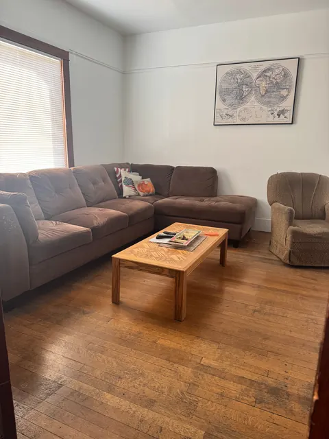 Living room at the 212 4th Ave E house with a sectional sofa, coffee table, armchair and hardwood floors