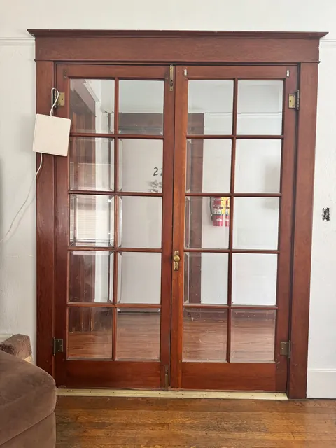 Wood-framed French doors with glass panes above a hardwood floor at the 212 4th Ave E house