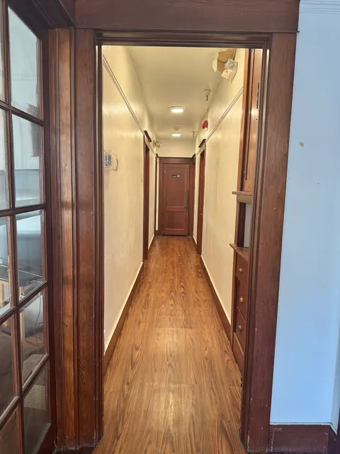 Hallway at the 212 4th Ave E house seen through a wood-trimmed doorway, with wood-look flooring