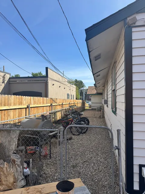 Gravel side yard at the 212 4th Ave E house with parked bicycles, a chain-link gate and wood fence