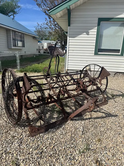 Antique farm implement with a metal seat displayed on gravel beside the 212 4th Ave E house
