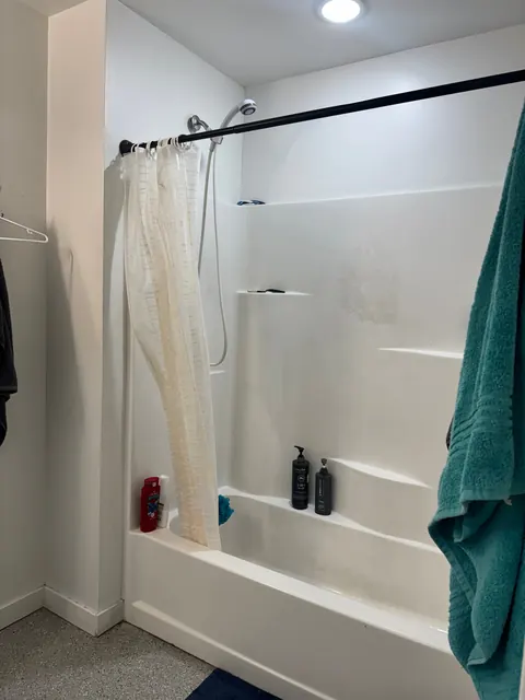 Bathroom at the 676 Shoup Ave W house with a white one-piece tub and shower surround and a shower curtain