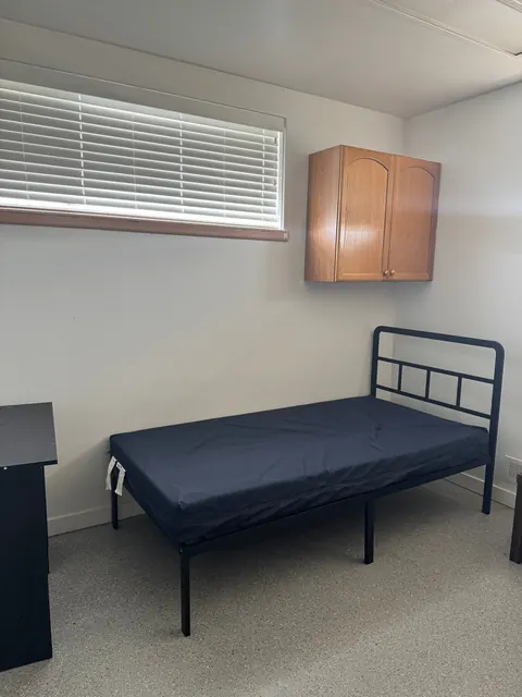 Bedroom with a twin bed, wall cabinet and window blinds at the 676 Shoup Ave W house