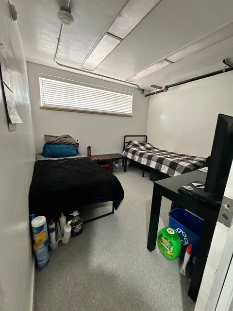 Two-bed bedroom at the 676 Shoup Ave W house with a high window, small side tables and a desk