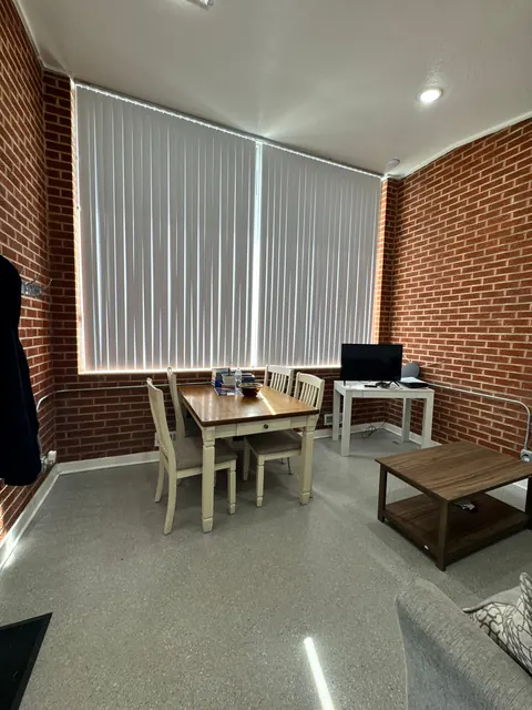 Dining area at the 676 Shoup Ave W house with a wood table, four chairs and tall windows with vertical blinds