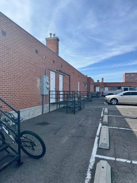 Brick building with white doors and metal stairs beside the parking lot at the 676 Shoup Ave W house