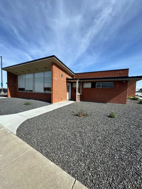 Front of the 676 Shoup Ave W house, a single-story red brick building with gravel landscaping and a curving walk