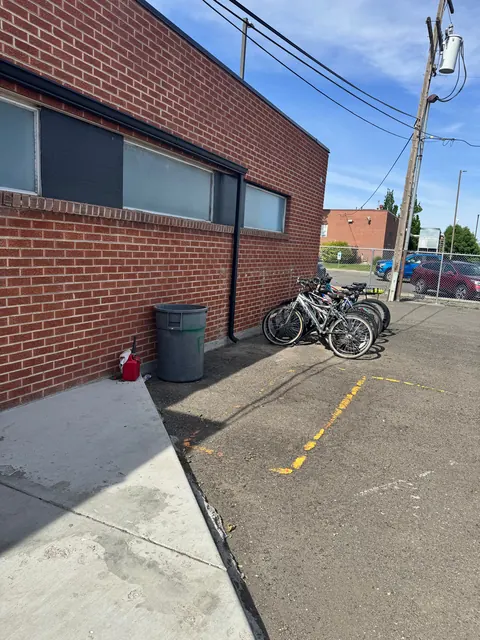 Brick side wall of the 676 Shoup Ave W house with parked bicycles, a trash can and a paved lot