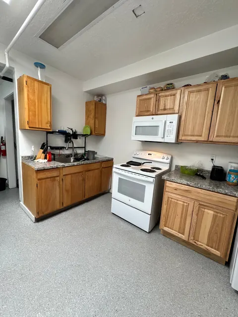 Wide view of the kitchen with two counters, a white stove and a microwave at the 676 Shoup Ave W house