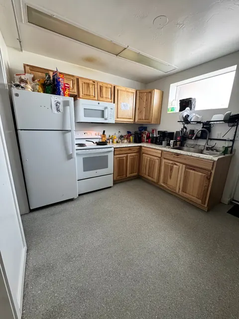 L-shaped kitchen at the 676 Shoup Ave W house with wood cabinets, white refrigerator, range and sink