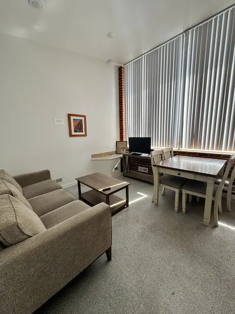 Living room with sofa, coffee table and dining table by tall windows at the 676 Shoup Ave W house