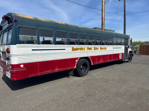 Side of the Realcovery Men's Sober Housing bus parked at the 676 Shoup Ave W house