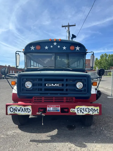 Front of the Realcovery bus with 'Onward to Freedom' bumper signs at the 676 Shoup Ave W house