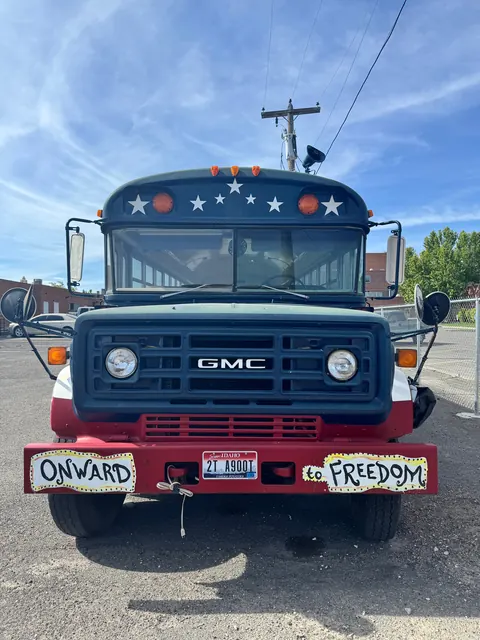 Front of the Realcovery bus with 'Onward to Freedom' signs, parked at the 676 Shoup Ave W house